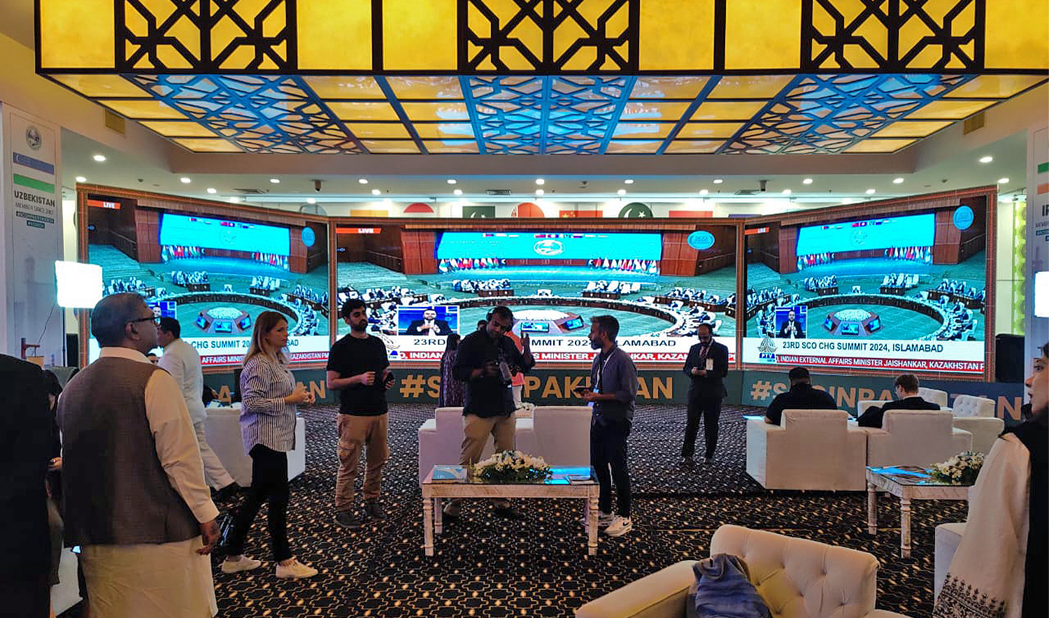 Media workers walk past screens airing the Shanghai Cooperation Organization (SCO) Summit in Islamabad, Pakistan, on October 16, 2024. (AN photo)