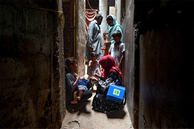 A health worker (front R) administers polio vaccine drops to a child during a polio vaccination campaign in Karachi on June 3, 2024. (AFP/File)