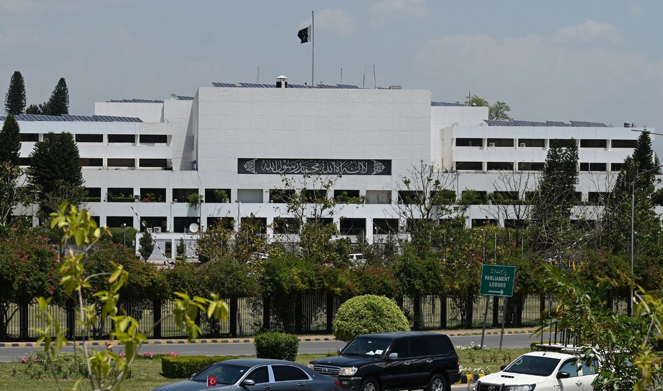 A car (L) carrying Turkey's Foreign Minister Hakan Fidan, drives past Pakistan's national flag at half mast atop the country's Parliament House in Islamabad on May 20, 2024. (AFP/File)