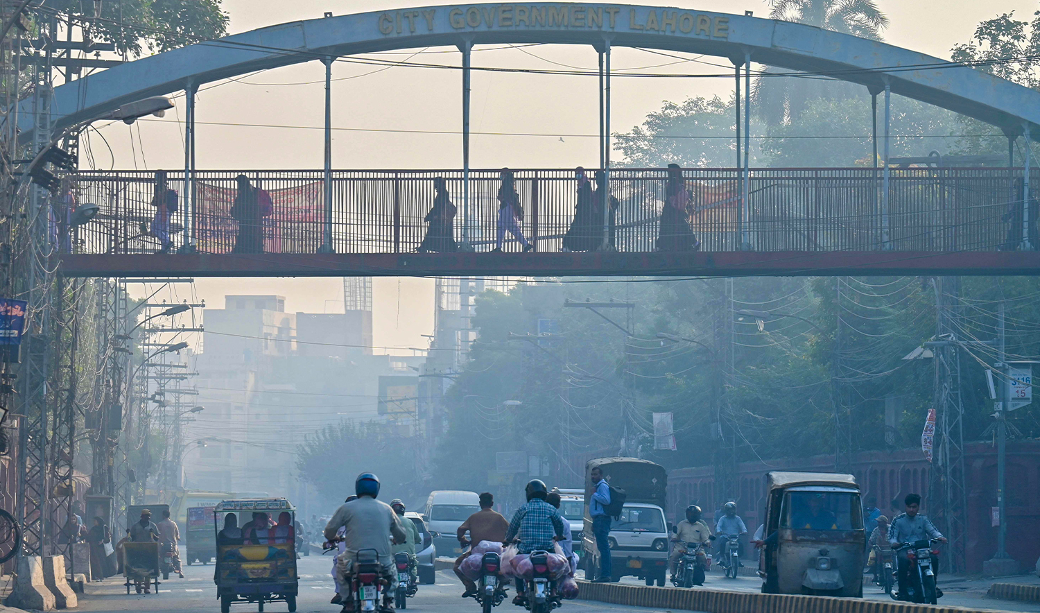 Commuters make their way amid heavy smog in Lahore on October 31, 2024. (AFP)