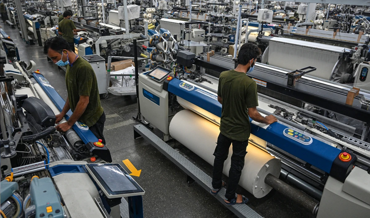 In this picture taken on July 20, 2023, workers operate machines at the Kohinoor Textile Mills in Lahore. (AFP/File)