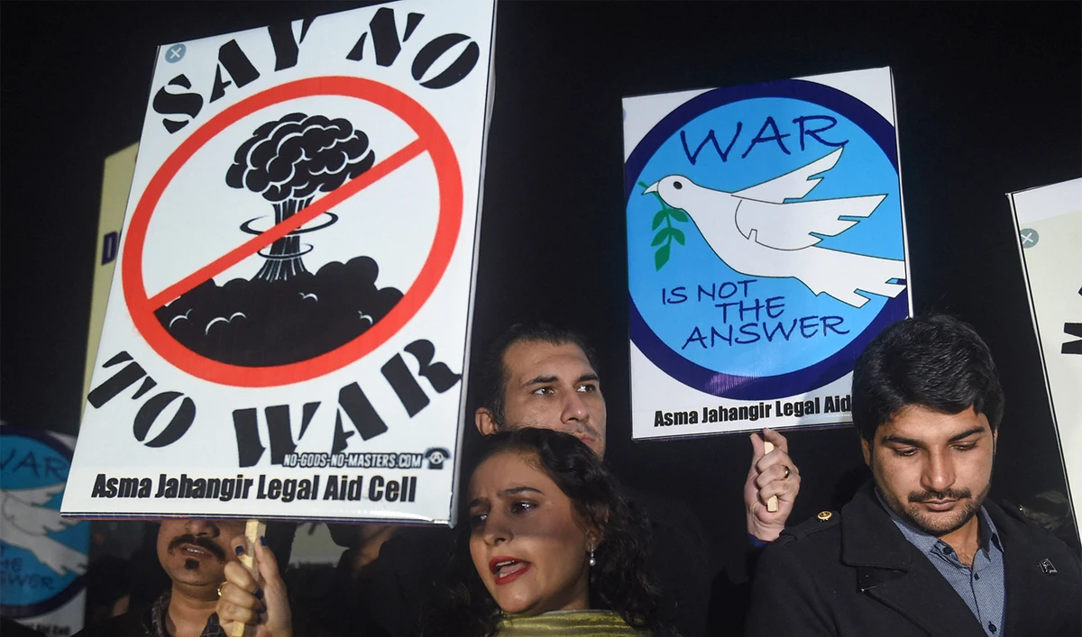 People hold signs reading "Say no to war" and "War is not the answer" during a vigil for peace in Lahore on March 3, 2019. (AFP/File)