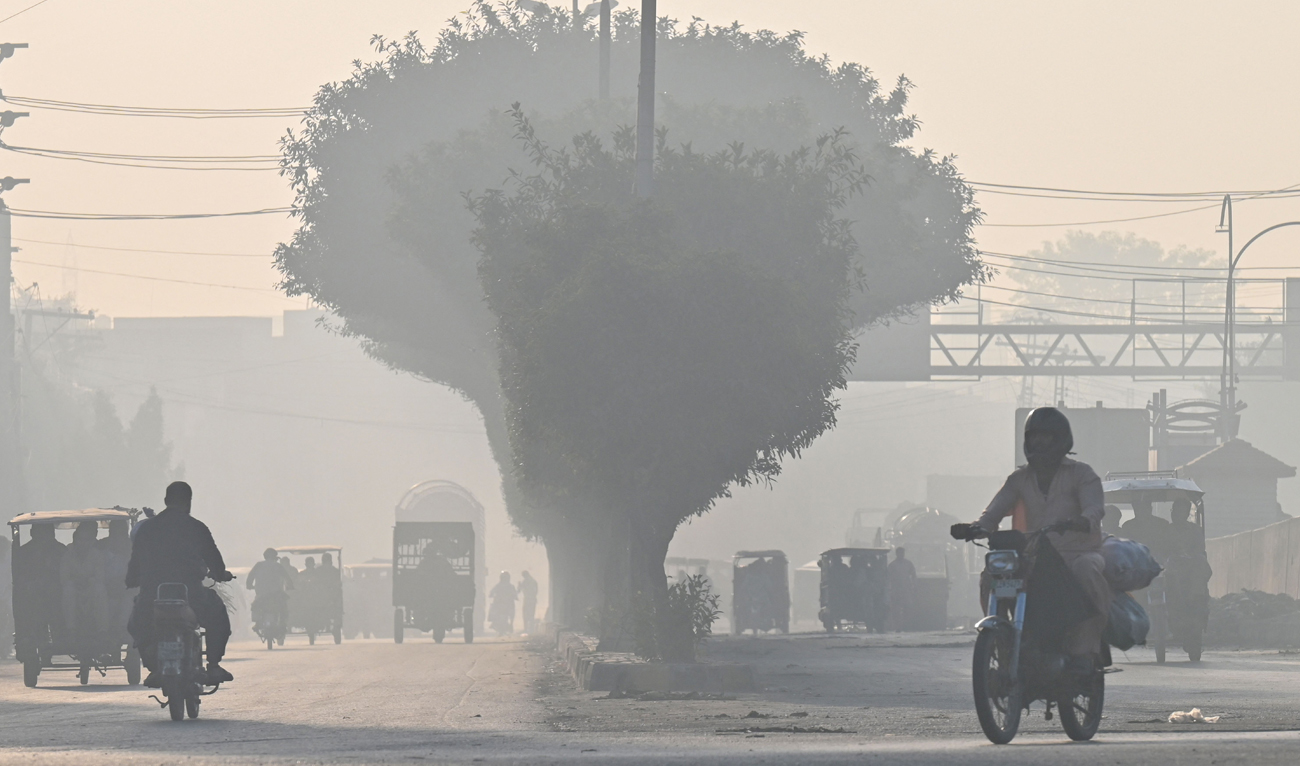 Commuters make their way amid smog in Lahore on November 1, 2024. (AFP)