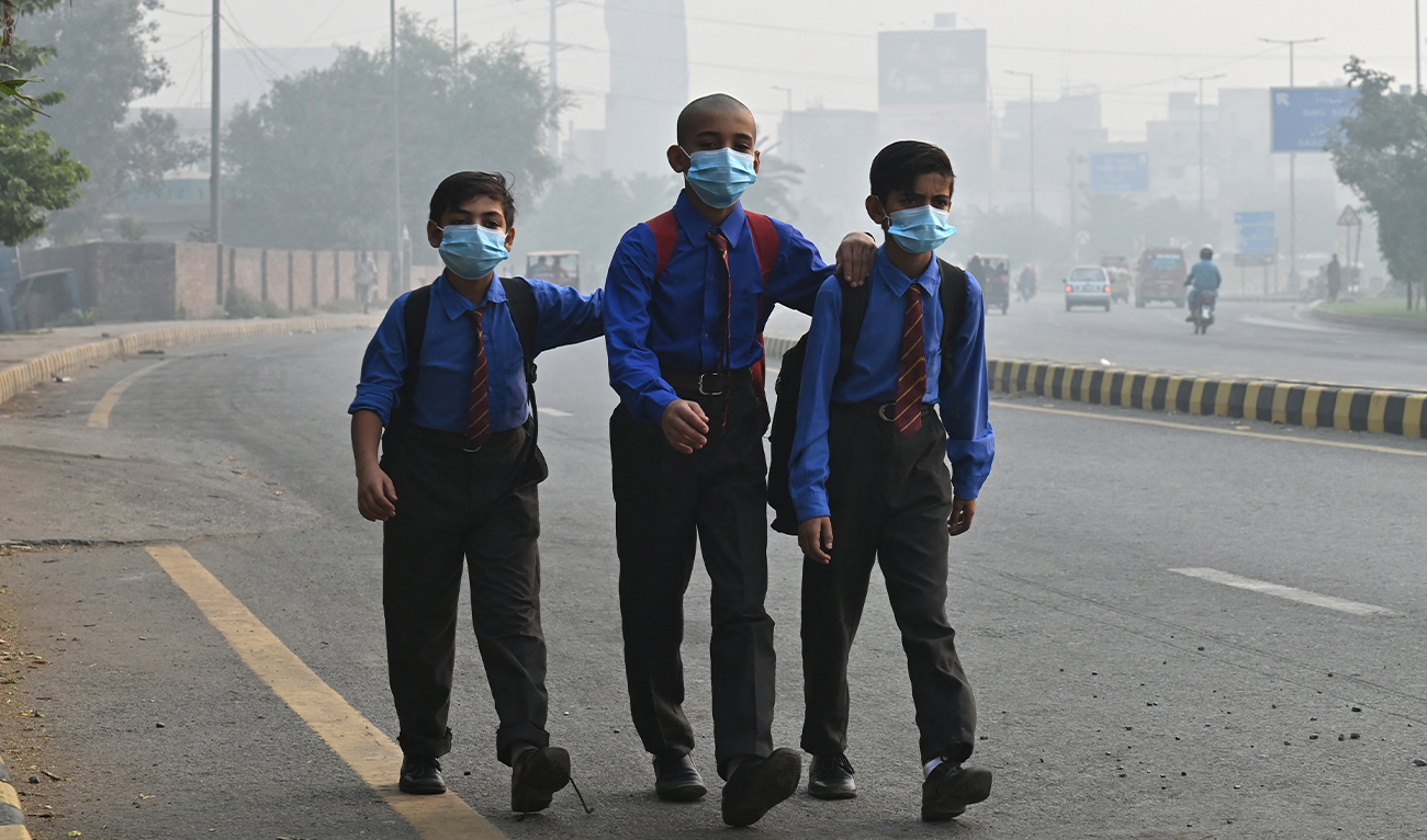 School boys wear masks as they walk along a road amid heavy smog in Lahore on October 29, 2024. (AFP)