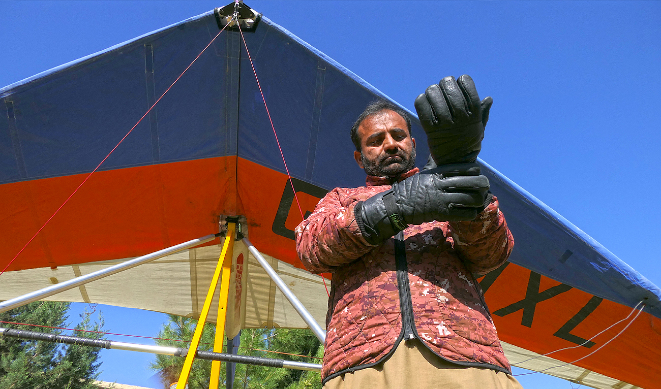 Muhammad Ashraf wears gloves before taking flight on his paramotor in Bostan, Pakistan's southwestern Balochistan province on November 03, 2024. (AN Photo)