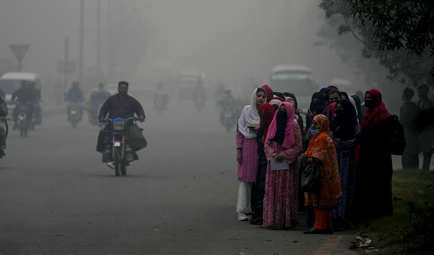 Students wait for transport in the morning at a roadside as smog envelops the area of Lahore, Pakistan, on November 8, 2024. (AP)