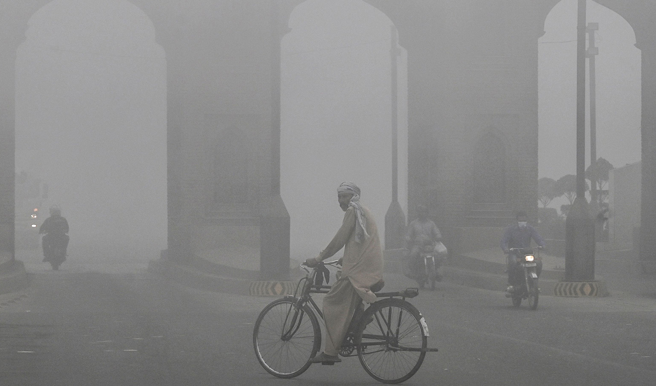 A cyclist rides along a street engulfed in thick smog, in Lahore on November 10, 2024. (AFP)