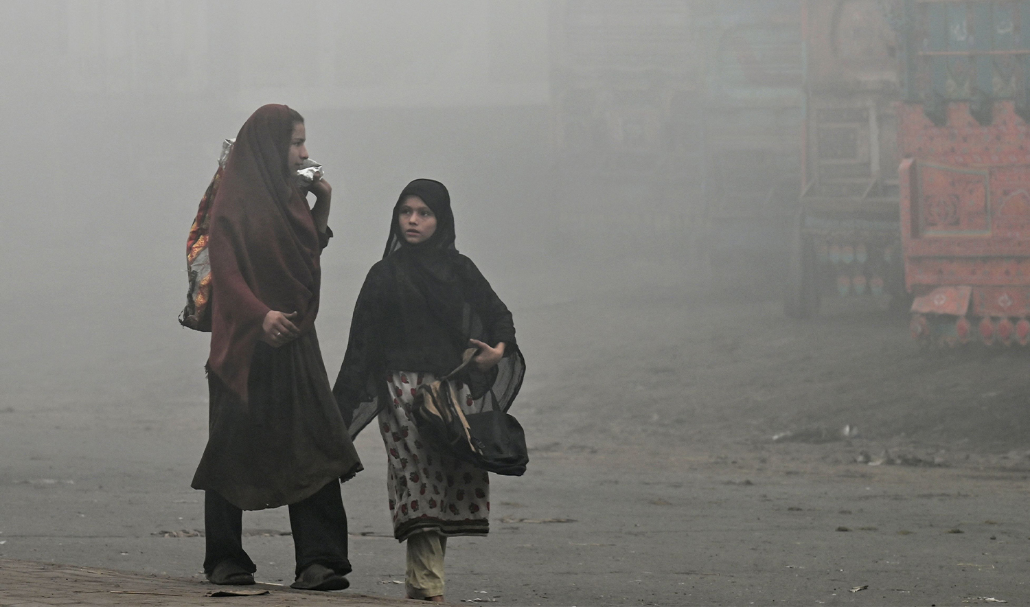 Pedestrians walk along a road engulfed in thick smog in Lahore on November 11, 2024. (AFP)