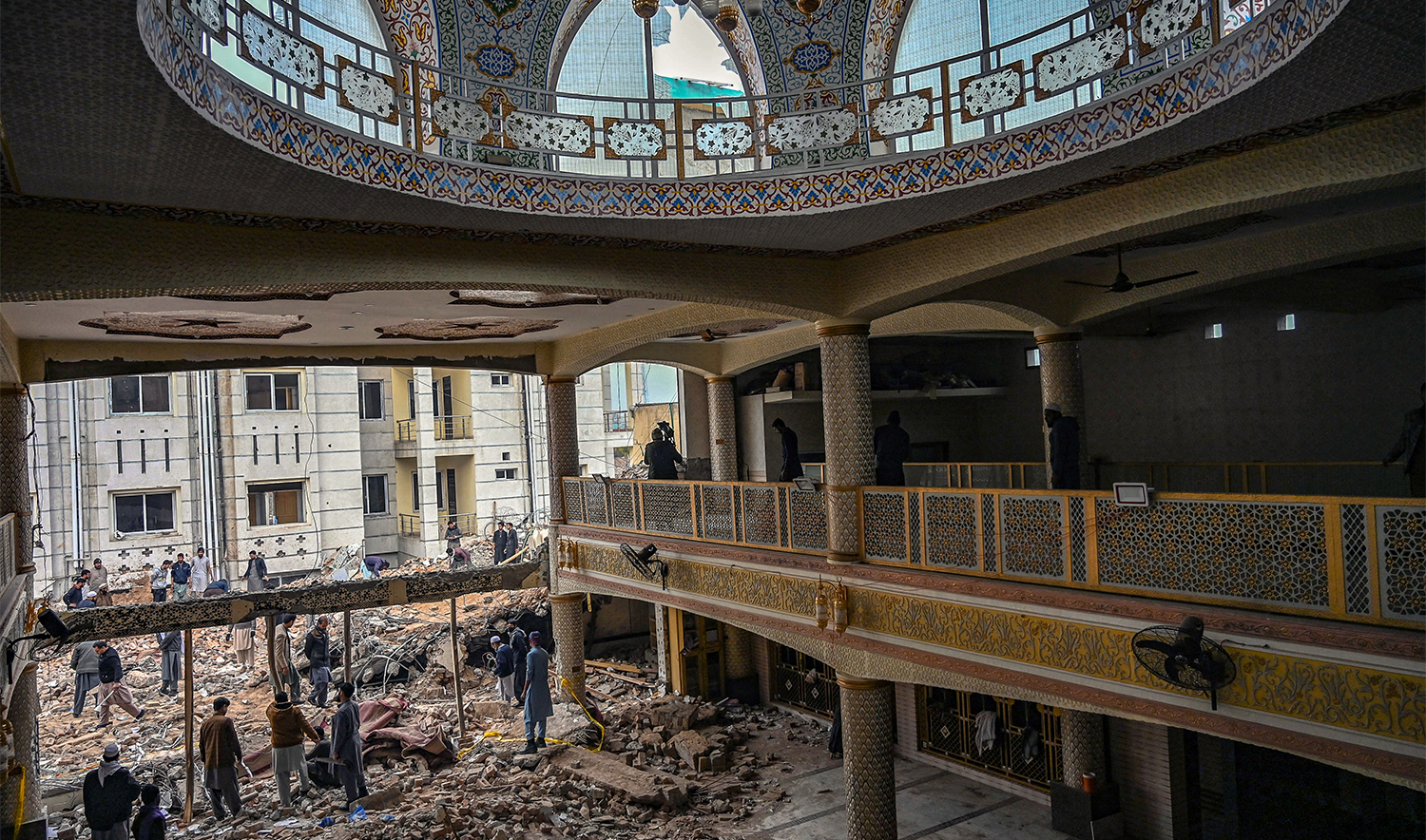 Plain-clothed policemen gather over the rubble of a damaged mosque following January's 30 suicide blast inside the police headquarters in Peshawar on February 1, 2023. (AFP/File)