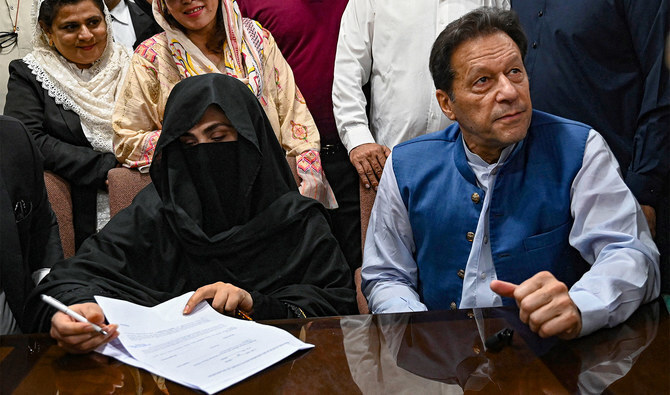 Pakistan's former Prime Minister, Imran Khan (R) along with his wife Bushra Bibi (L) looks on as he signs surety bonds for bail in various cases, at a registrar office in the High court, in Lahore on July 17, 2023. (AFP/File)