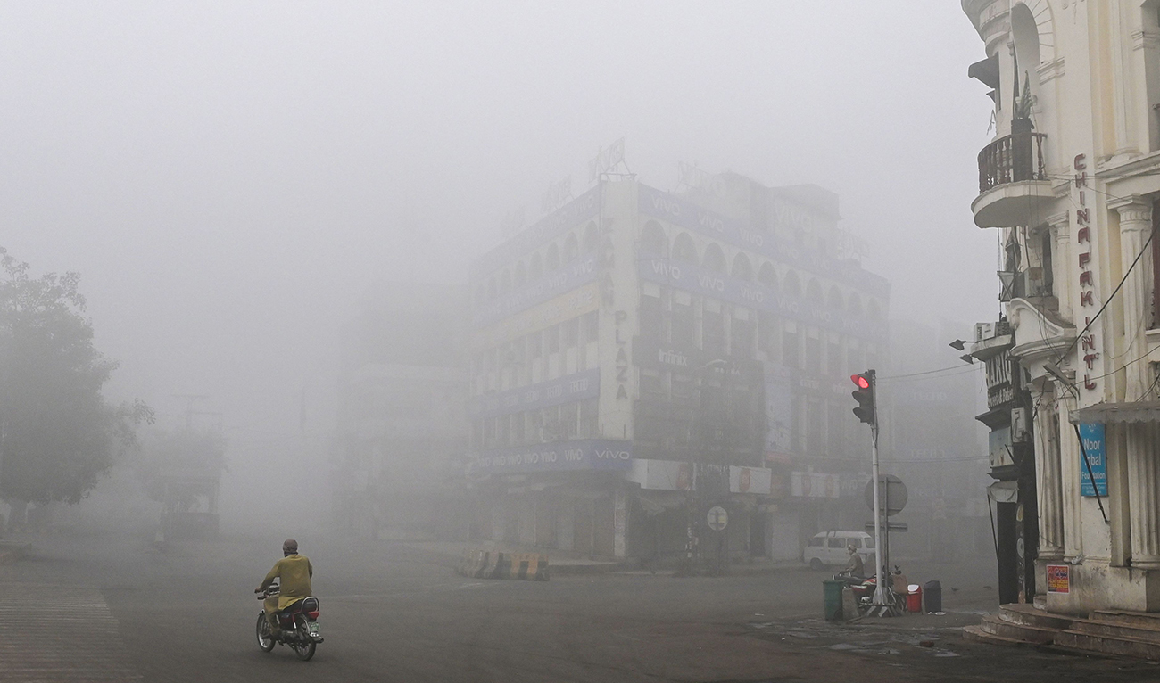 A man rides his motorbike along a street engulfed in smog in Lahore on November 14, 2024. (AFP)