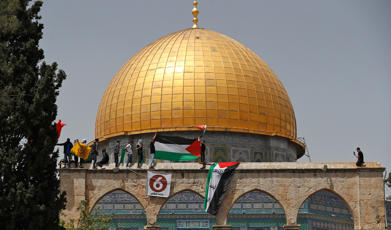 Palestinians wave national flags as they rally by the Dome of the Rock mosque at the Al-Aqsa Mosque complex in Jerusalem, on April 29, 2022 (AFP/File)