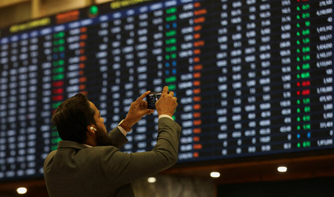 A man uses a mobile phone as he takes a photo of the electronic board displaying share prices during a trading session at the Pakistan Stock Exchange, in Karachi, Pakistan on November 28, 2023. (REUTERS/File)
