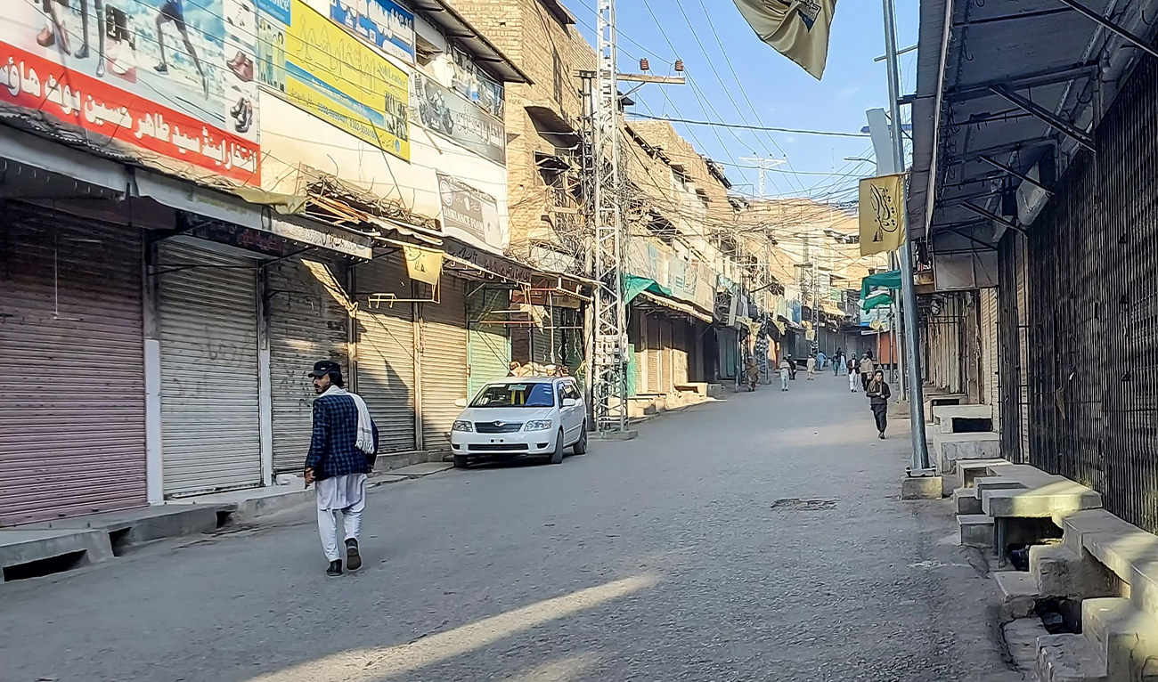 Men walk past a market closed by traders during a strike against sectarian attacks in district Kurram, Pakistan, on November 22, 2024. (AFP)