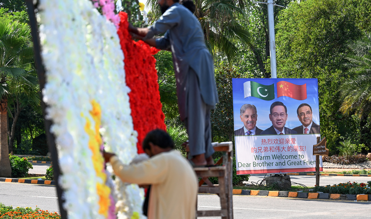 Workers decorate a street near a billboard featuring images of China’s Premier Li Qiang (C), Pakistan’s Prime Minister Shehbaz Sharif and President Asif Ali Zardari (R) ahead of the Shanghai Cooperation Organization (SCO) summit in Islamabad on October 13, 2024. (AFP/File)