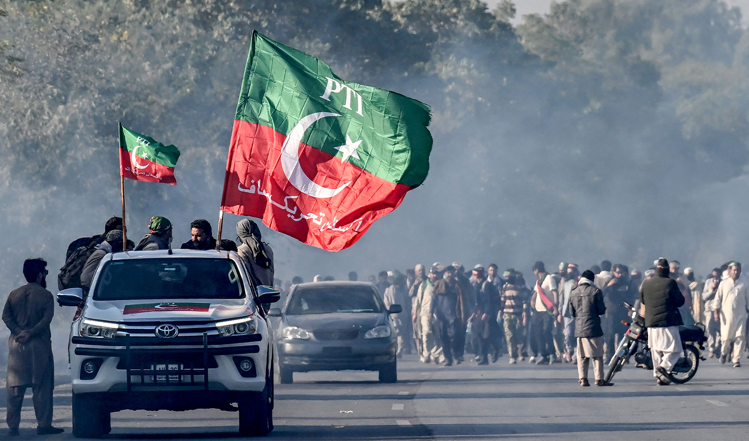 Supporters of jailed former prime minister Imran Khan's Pakistan Tehreek-e-Insaf (PTI) party march towards Islamabad after clearing shipping containers placed by authorities during a demonstration demanding Khan's release, in Hasan Abdal in Punjab province on November 25, 2024. (AFP)