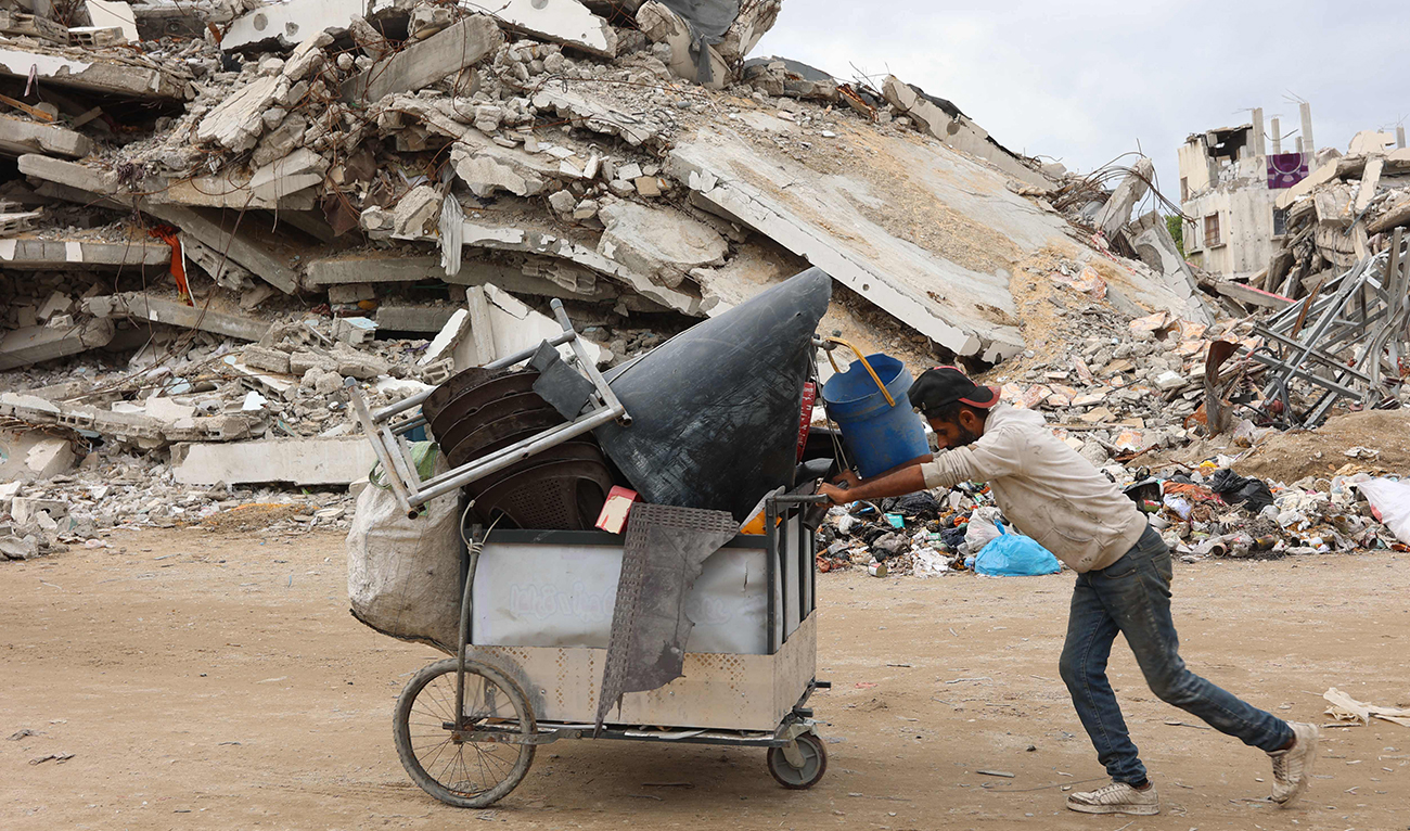 A Palestinian man pushes a cart past a destroyed building west of Gaza City, on November 25, 2024, amid the ongoing conflict between Israel and the Hamas group. (AFP)