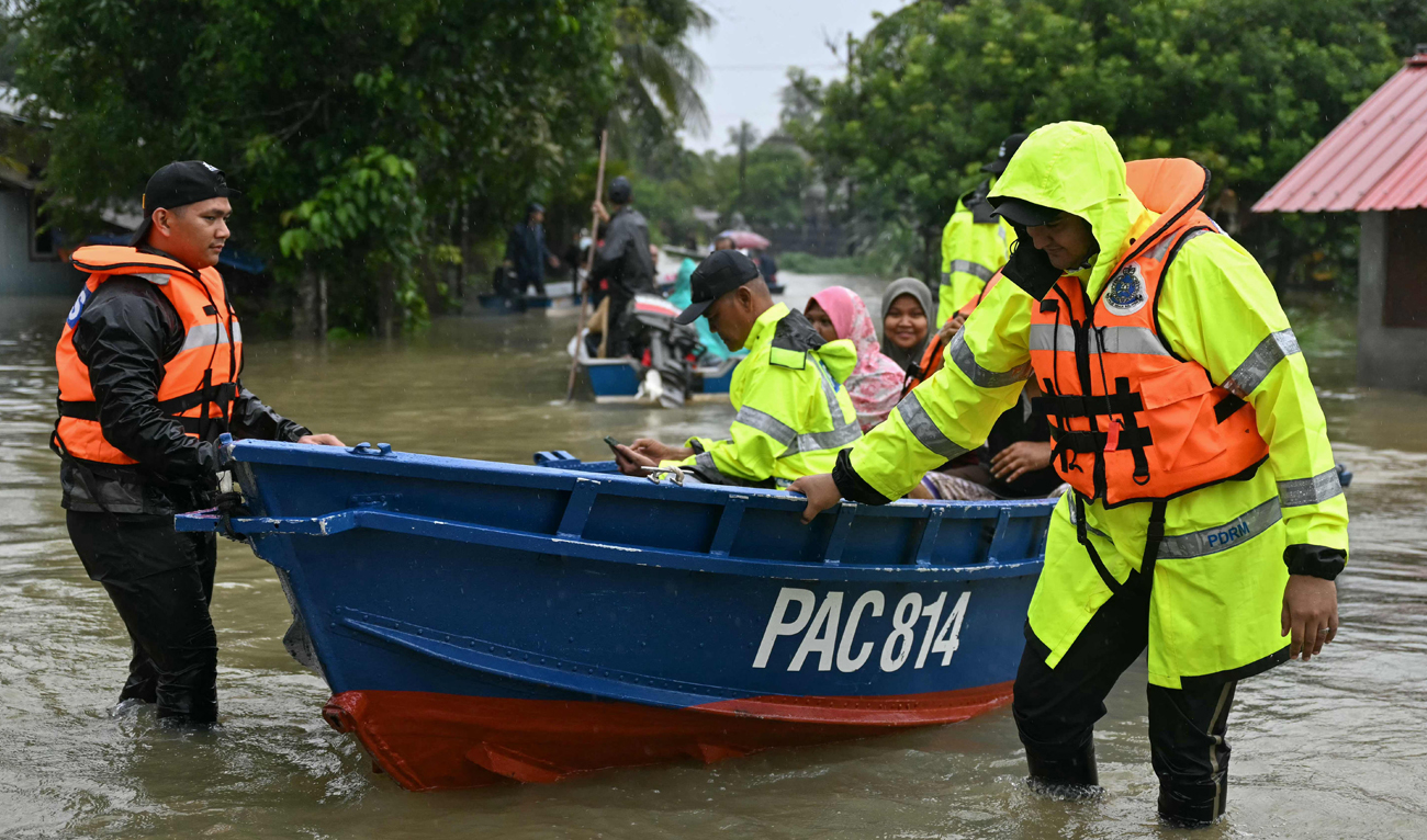 Royal Malaysia Police transport residents on a boat through flood waters after days of heavy rain in Tumpat in Malaysia’s Kelantan state on November 30, 2024. (AFP)