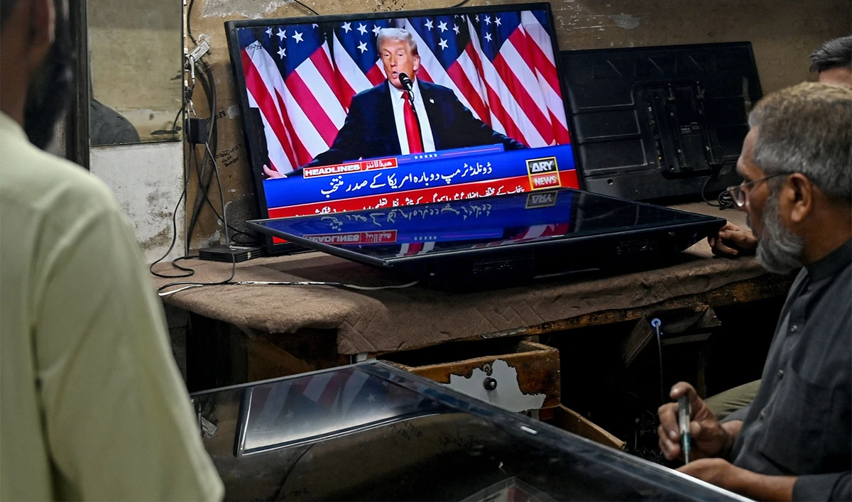 Men watch a television broadcast featuring US former president and Republican presidential candidate Donald Trump at a workshop in Karachi on November 6, 2024. (AFP)