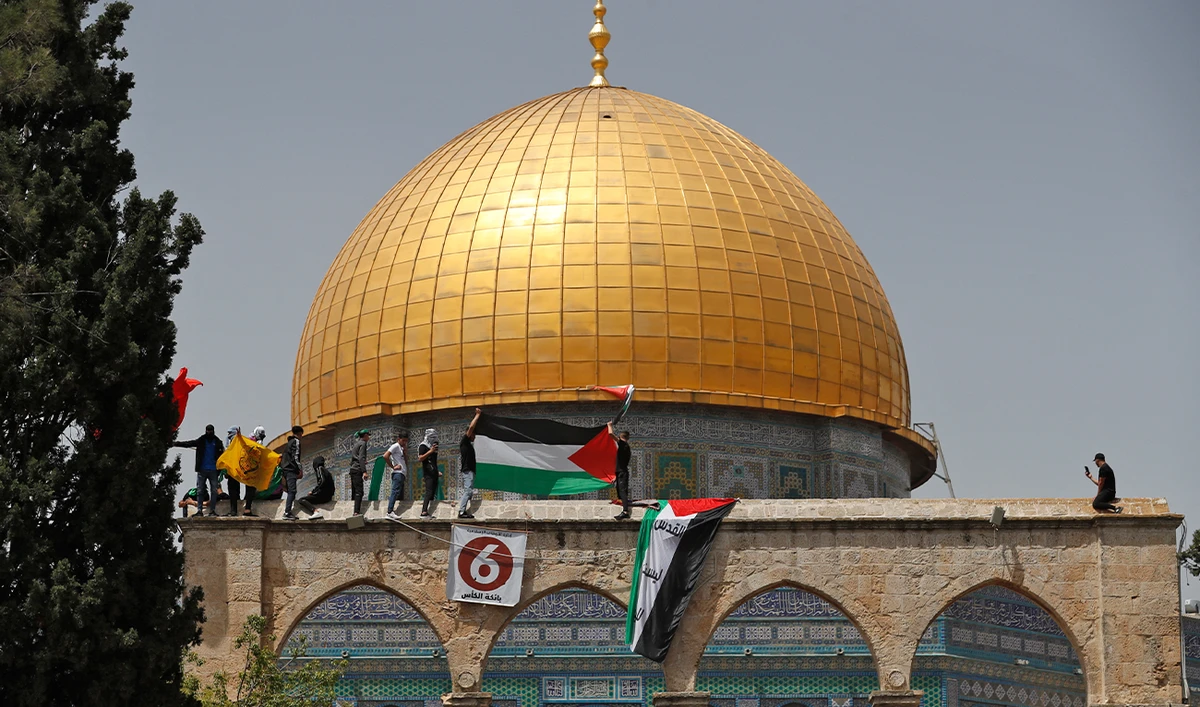 Palestinians wave national flags as they rally by the Dome of the Rock mosque at the Al-Aqsa Mosque complex in Jerusalem, on April 29, 2022 (AFP/File)