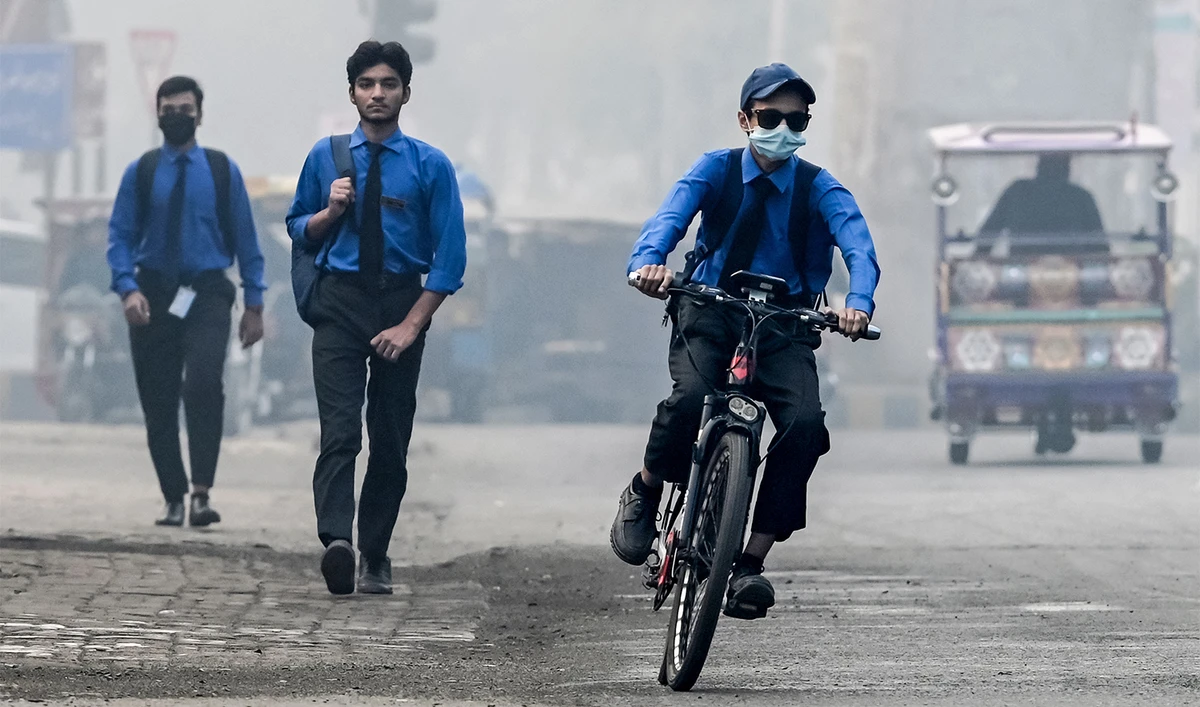 A student wearing a mask rides a bicycle to school along a street engulfed in smog, in Lahore on November 5, 2024. (AFP/File)