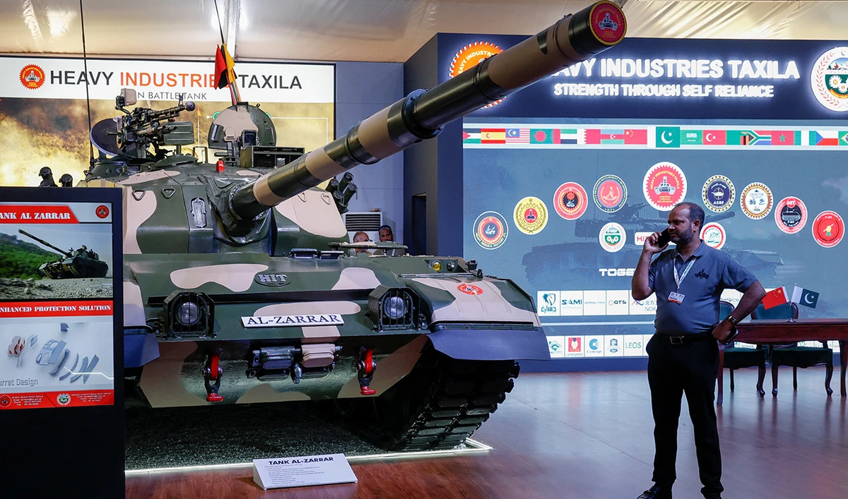 A visitor uses his mobile phone while visiting the stall of the AL-Zarrar tank on display during the International Defense Exhibition and Seminar “IDEAS 2024” in Karachi on November 21, 2024. (REUTERS)
