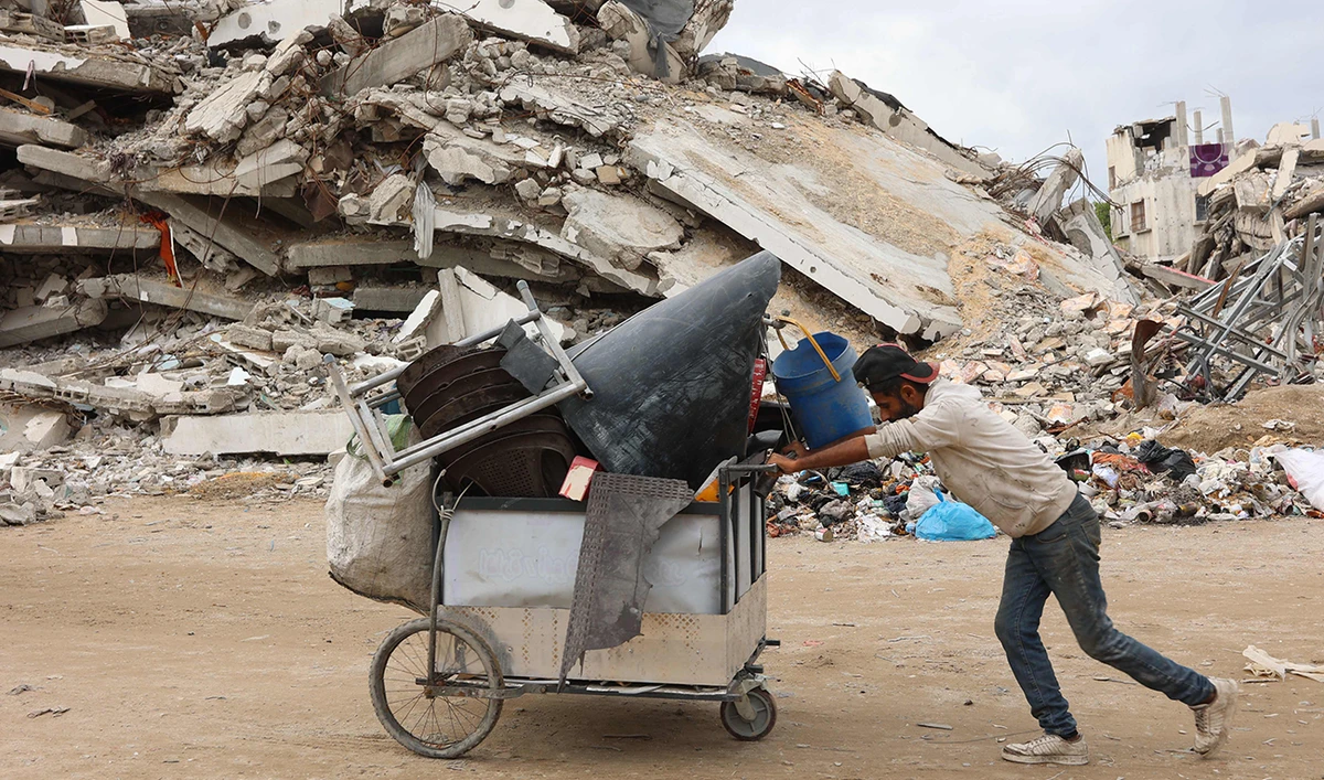 A Palestinian man pushes a cart past a destroyed building west of Gaza City, on November 25, 2024, amid the ongoing conflict between Israel and the Hamas group. (AFP)