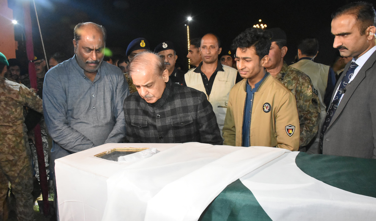 In this handout photograph, released by Pakistan’s Inter-Services Public Relations (ISPR), Pakistan Prime Minister Shehbaz Sharif (2L) and family members take a last glimpse at the body of Pakistani Army Captain Muhammad Zohaib Ud Din, who was killed in the ongoing operation against militants in Khyber district, during his funeral ceremony in Lahore on December 1, 2024. (ISPR)