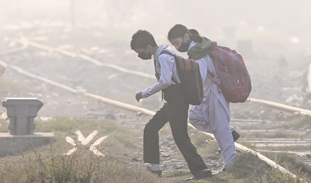 School children wearing facemasks walk across a railway track amid thick smog in Lahore, Pakistan, on November 20, 2024. (AFP/File)