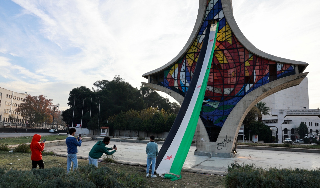People take pictures next to the Syrian opposition flag after rebels seized the capital and ousted President Bashar al-Assad in Damascus, Syria, on December 12, 2024. (REUTERS)