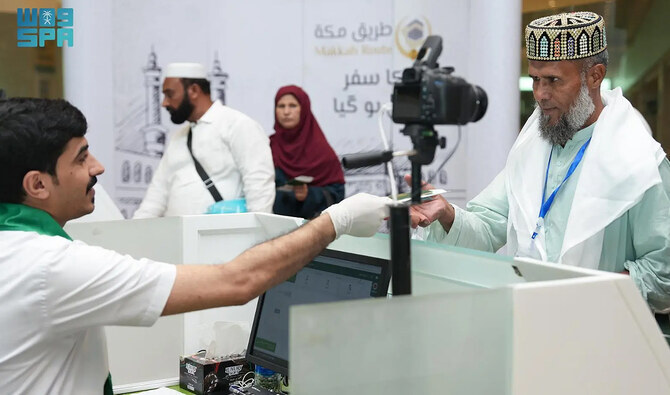 In this file photo, taken and released by the Saudi Press Agency on May 26, 2024, Saudi official handover passport to a Pakistani pilgrim at the Jinnah Internation Airport in Karachi. (SPA/File)