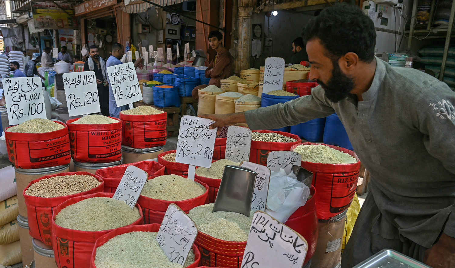 A shopkeeper arranges price tags on rice sacks at his grocery shop in Karachi on September 26, 2024. (AFP/File)