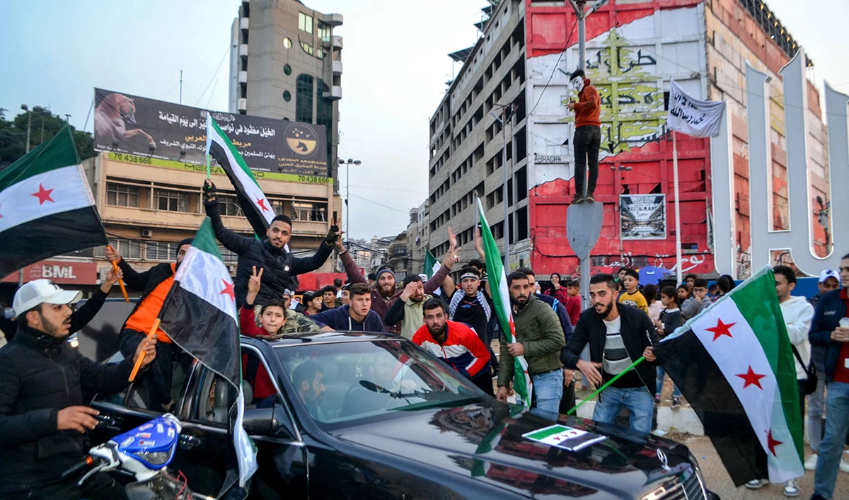 Syrian and Lebanese people in the northern Lebanese city of Tripoli celebrate on December 9, 2024, after the opposition forces declared that they have taken the Syrian capital in a lightning offensive, sending President Bashar Assad fleeing and ending six decades of his family’s autocratic rule in Syria. (AFP)