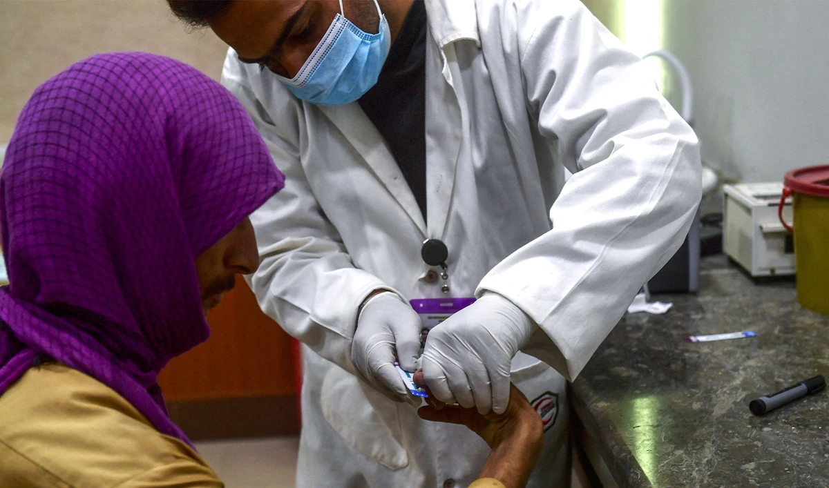 In this picture taken on March 26, 2021, a laboratory technician takes a blood sample from a man for an HIV test at a HIV treatment support centre in Rato Dero, in southern Sindh province. (AFP/File)