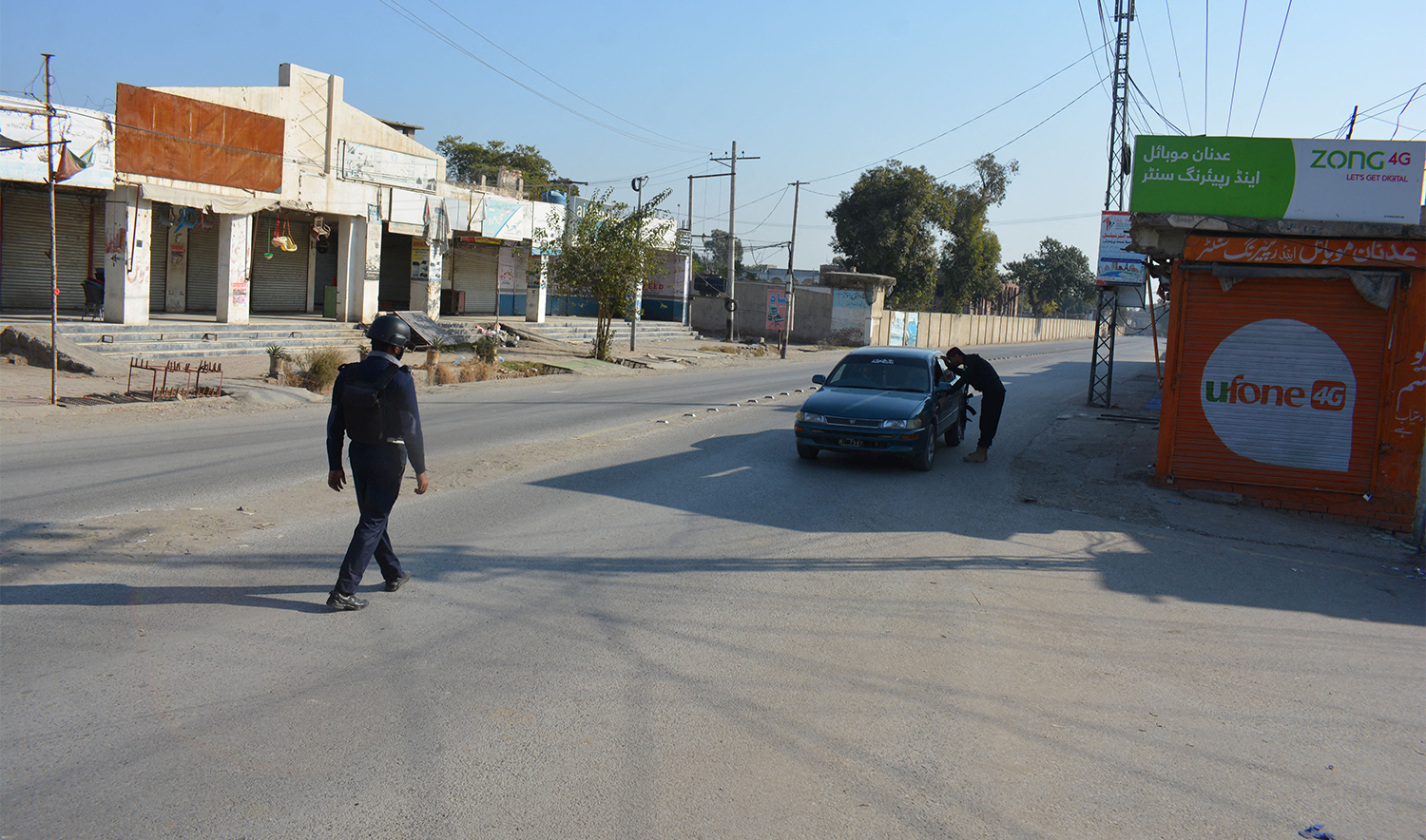 A Pakistani policeman checks a car in front of a shuttered market after Taliban militants seized a police station in Bannu on December 20, 2022. (AFP/File)