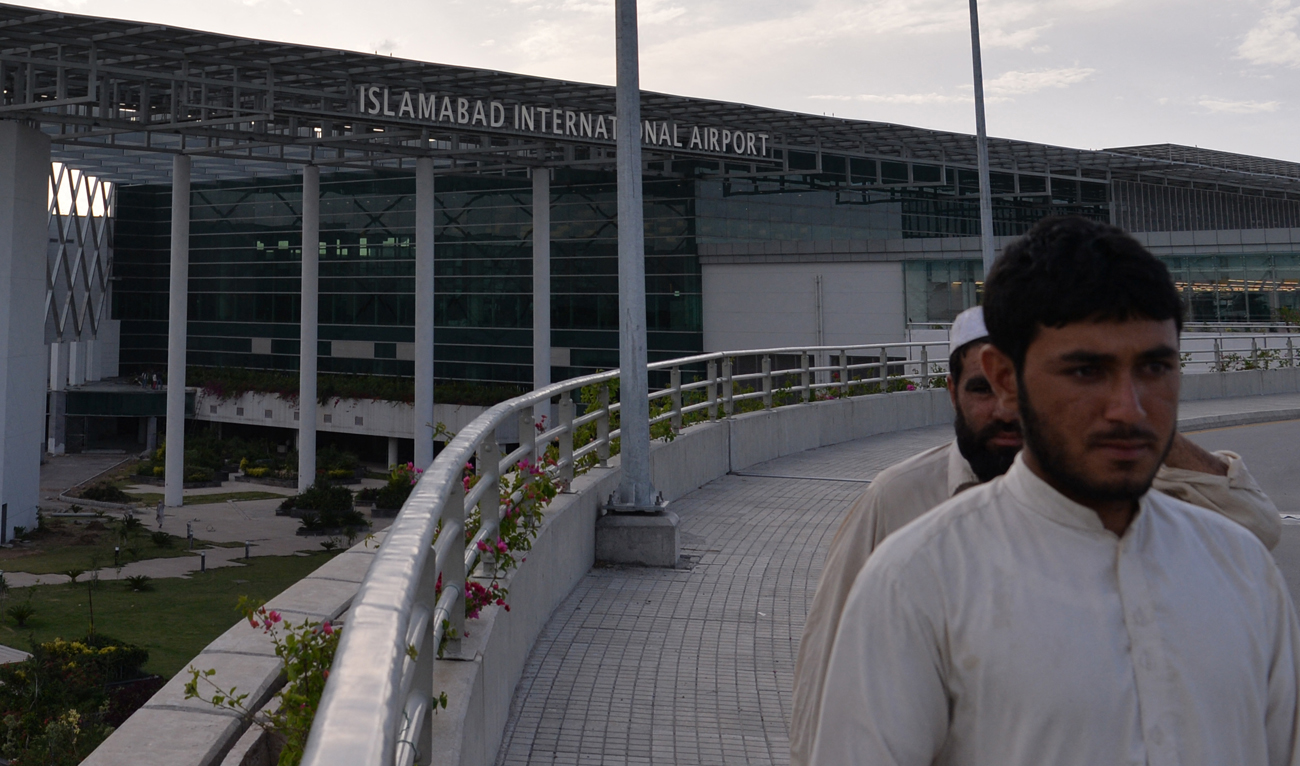 In this file photo, taken on April 18, 2018, Pakistani workers walk past the Islamabad International Airport on the outskirts of Islamabad. (AFP/File)