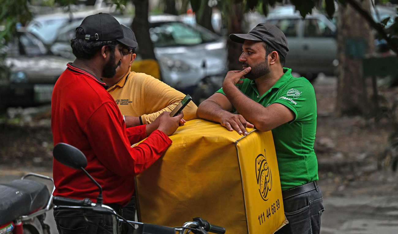 A food delivery man uses his mobile phone near a restaurant in Islamabad on August 17, 2024. (AFP/File)