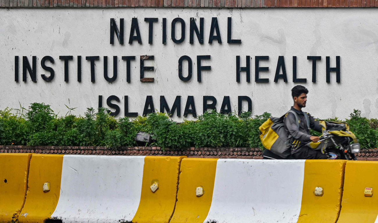 A delivery boy rides past the building of National Institute of Health (NIH), a Pakistani research institute mainly responsible for biomedical and health related research, in Islamabad on August 16, 2024. (AFP/File)