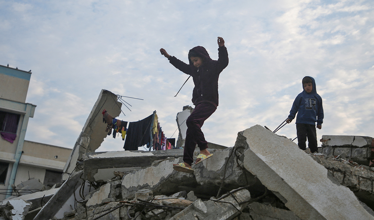 A Palestinian child jumps down from the rubble of a building destroyed in previous Israeli strikes, ahead of a ceasefire set to take effect on Sunday, in Gaza City on January 16, 2025. (REUTERS)