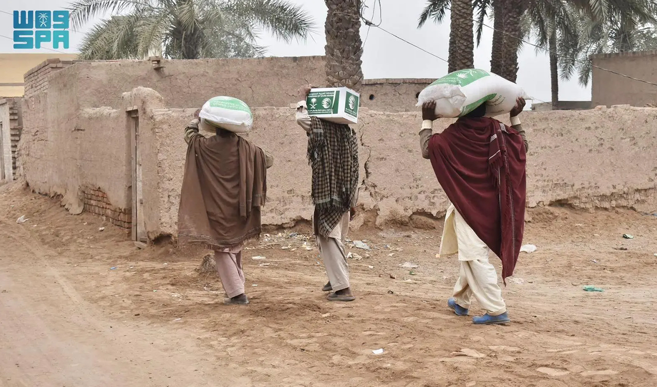 This handout photo, taken and released by Saudi Press Agency on January 21, 2025, shows Pakistani man carrying aid received by King Salman Humanitarian Aid and Relief Center (KSrelief) in Dadu, Sindh. (SPA)