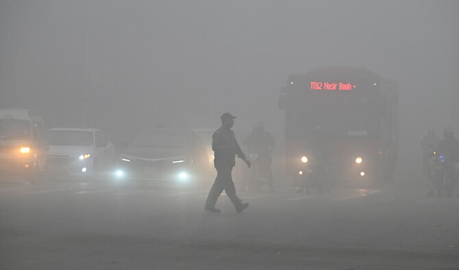 A man crosses a street engulfed in smog in Lahore on November 16, 2024. Pakistan’s most populated province of Punjab on on November 15 extended school closures in smog-hit major cities by a week, with thousands hospitalized as the country battles record air pollution. (AFP/File)