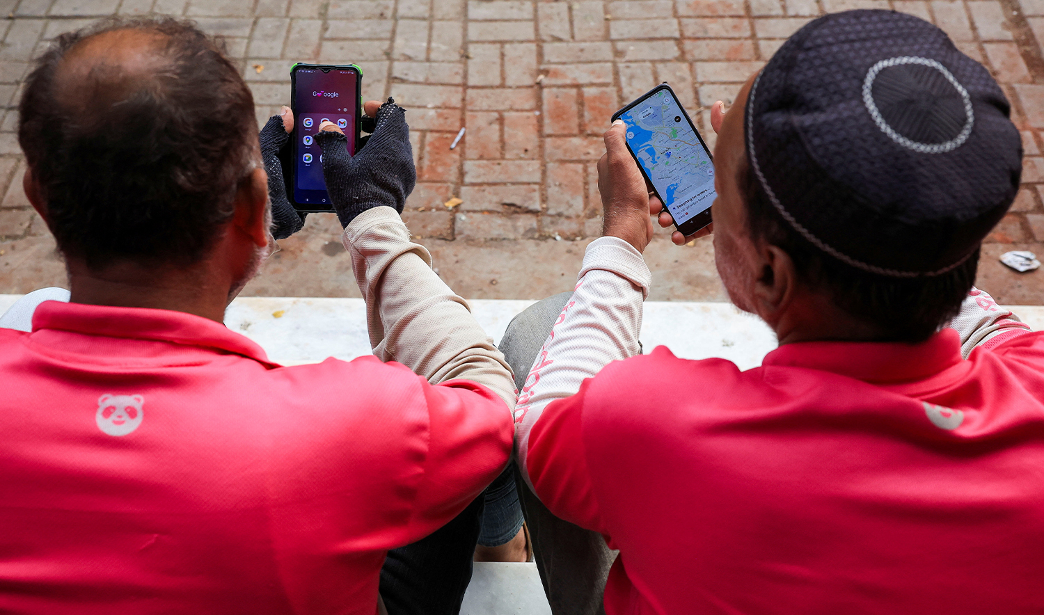 Riders check their mobile phones for online food orders from customers, while waiting outside an office in Karachi, Pakistan August 22, 2024. (REUTERS/File)