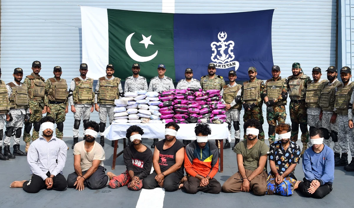 In this handout photo, released by Pakistan Navy on January 1, 2025, Pakistani security personnel gesture with suspects detained with ‘large cache of narcotics’ during a counter-narcotics operation at the Arabian Sea. (Photo courtesy: Pakistan Navy)