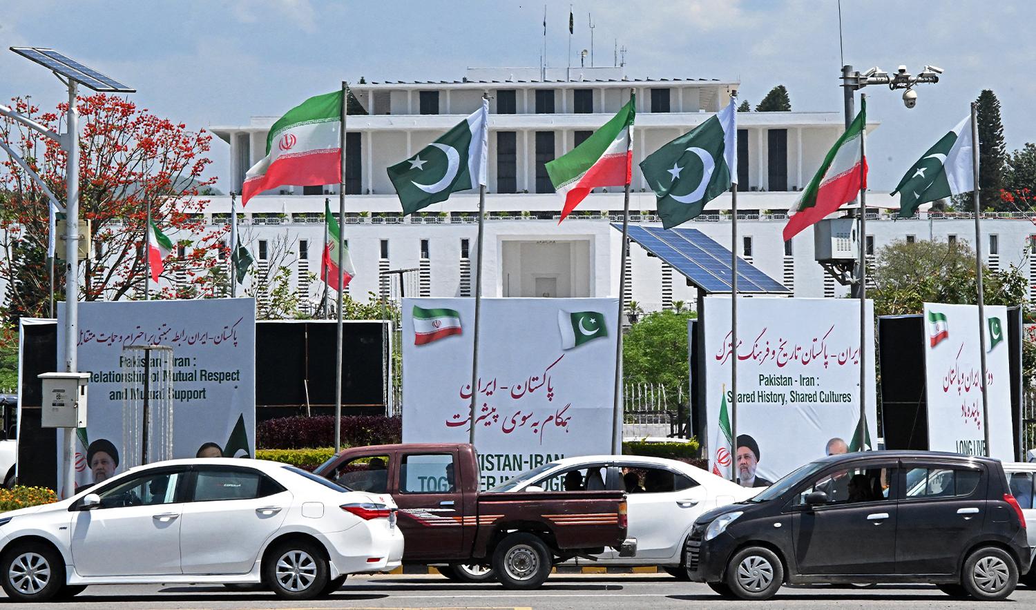 Commuters make their way past the welcoming billboards installed at the constitution avenue for the visit of late Iranian President Ebrahim Raisi, in Islamabad on April 22, 2024. (AFP/File)