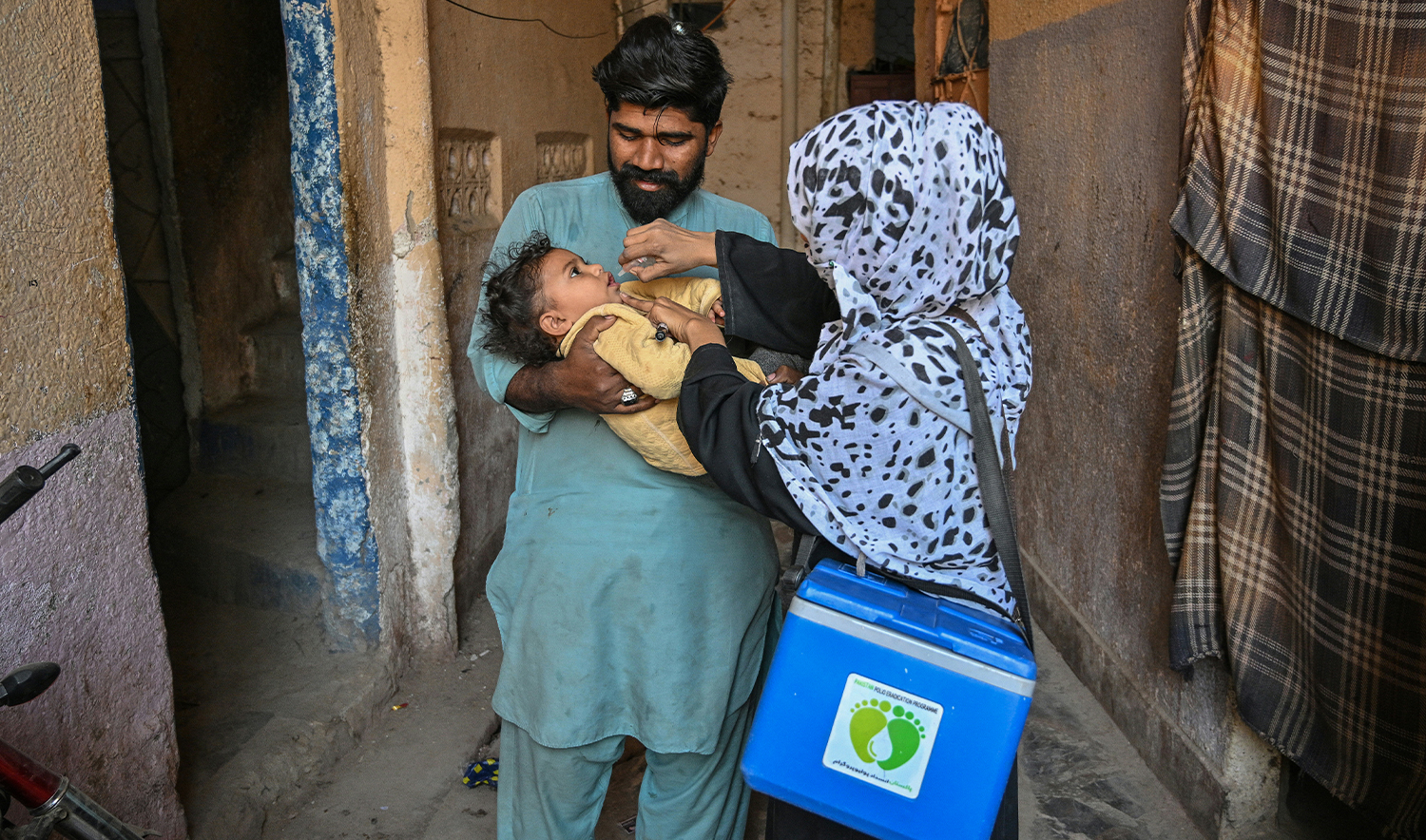 A health worker (R) administers polio drops to a child on the first day of a nationwide polio vaccination campaign, in Karachi on February 3, 2025. (AFP/File)