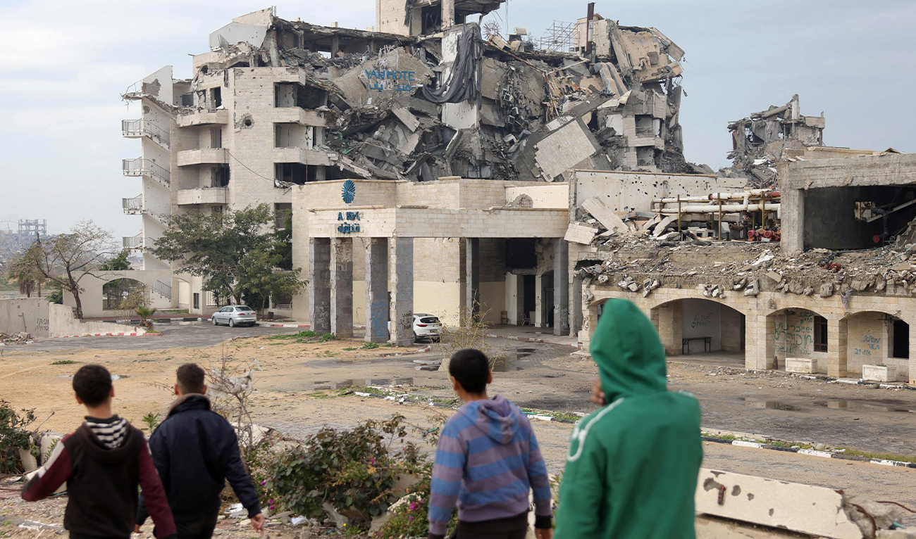 People walk past the heavily damaged Ayan Hotel in northern Gaza City on February 11, 2025. (AFP)