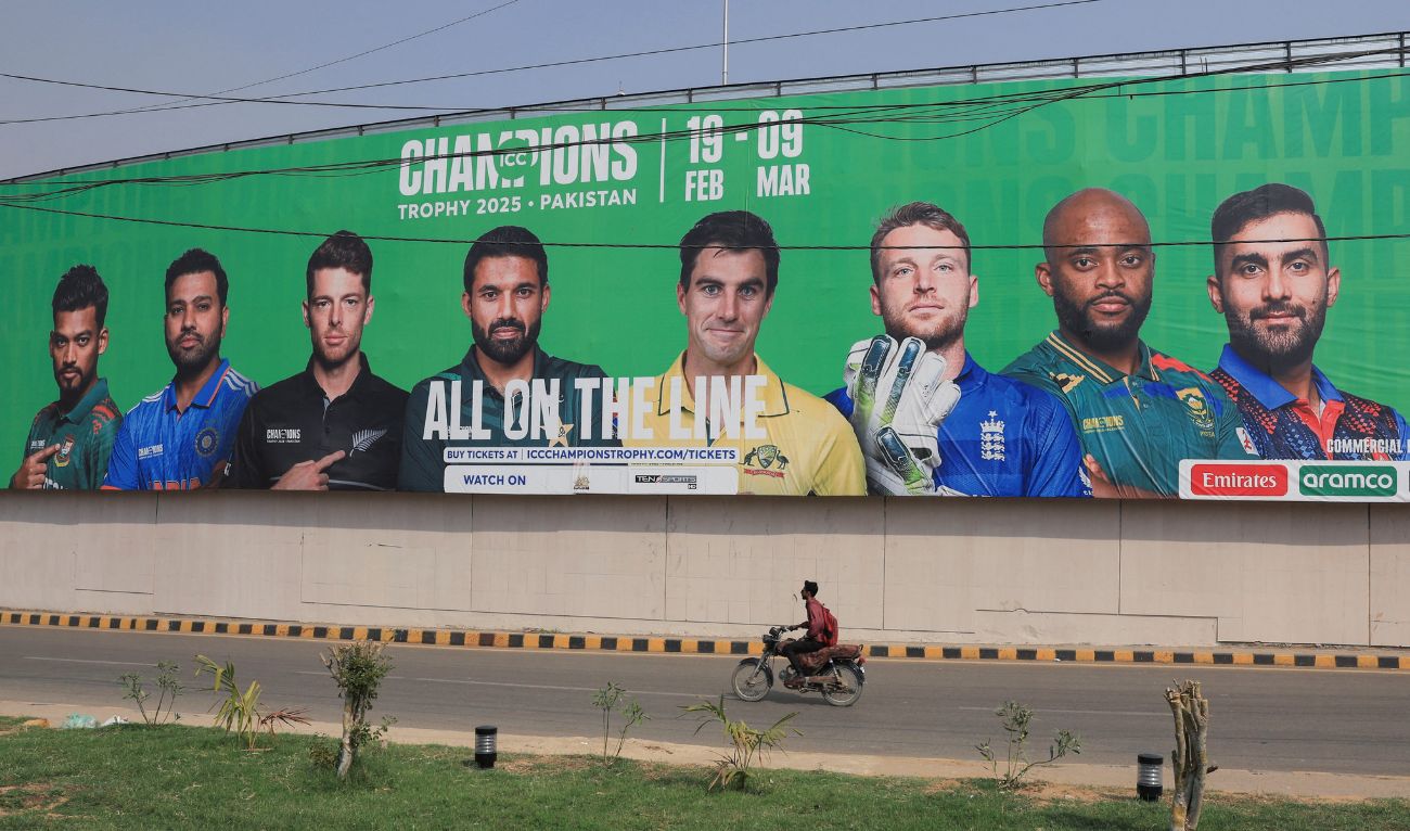 A person rides on a motorbike past a wall with a billboard advertisment ahead of the ICC Champions Trophy 2025 tournament, in Karachi. (Reuters)