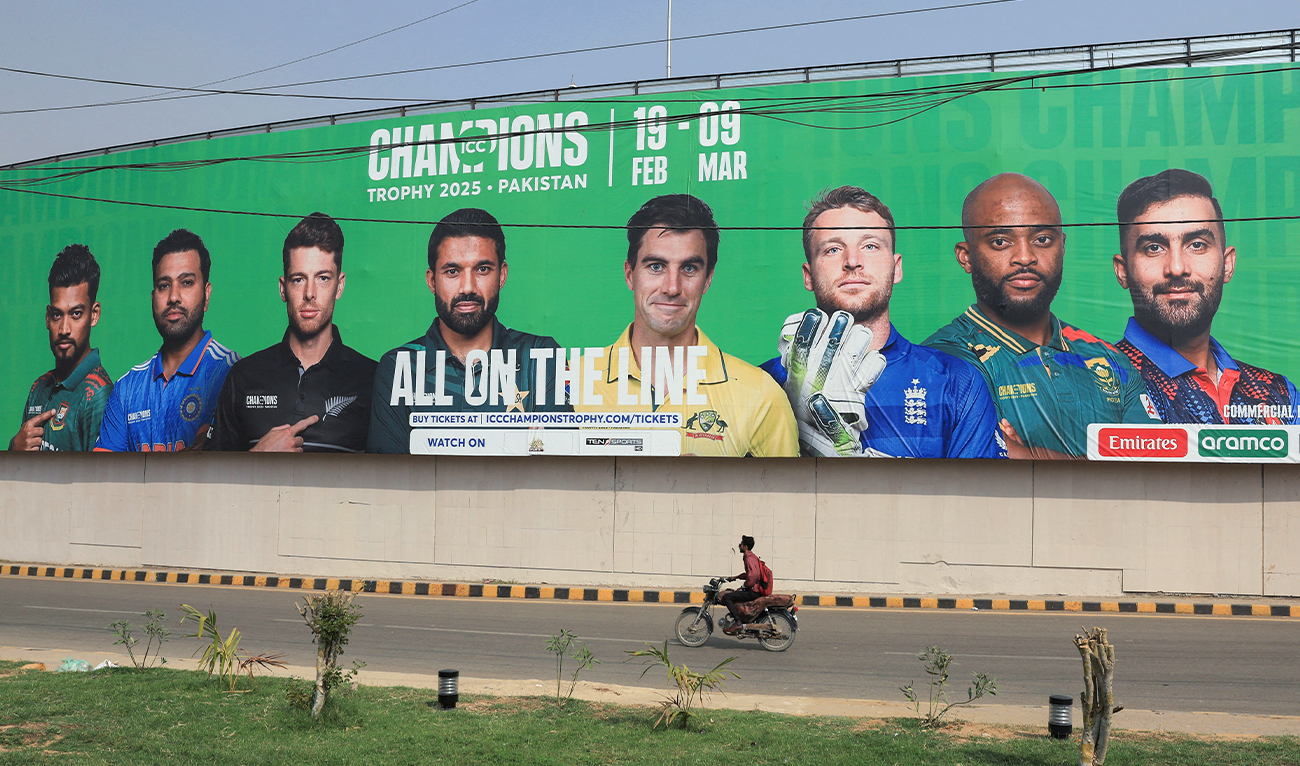 A person rides on a motorbike past a wall with a billboard advertisement ahead of the ICC Champions Trophy 2025 tournament in Karachi, Pakistan, on February 13, 2025. (REUTERS)