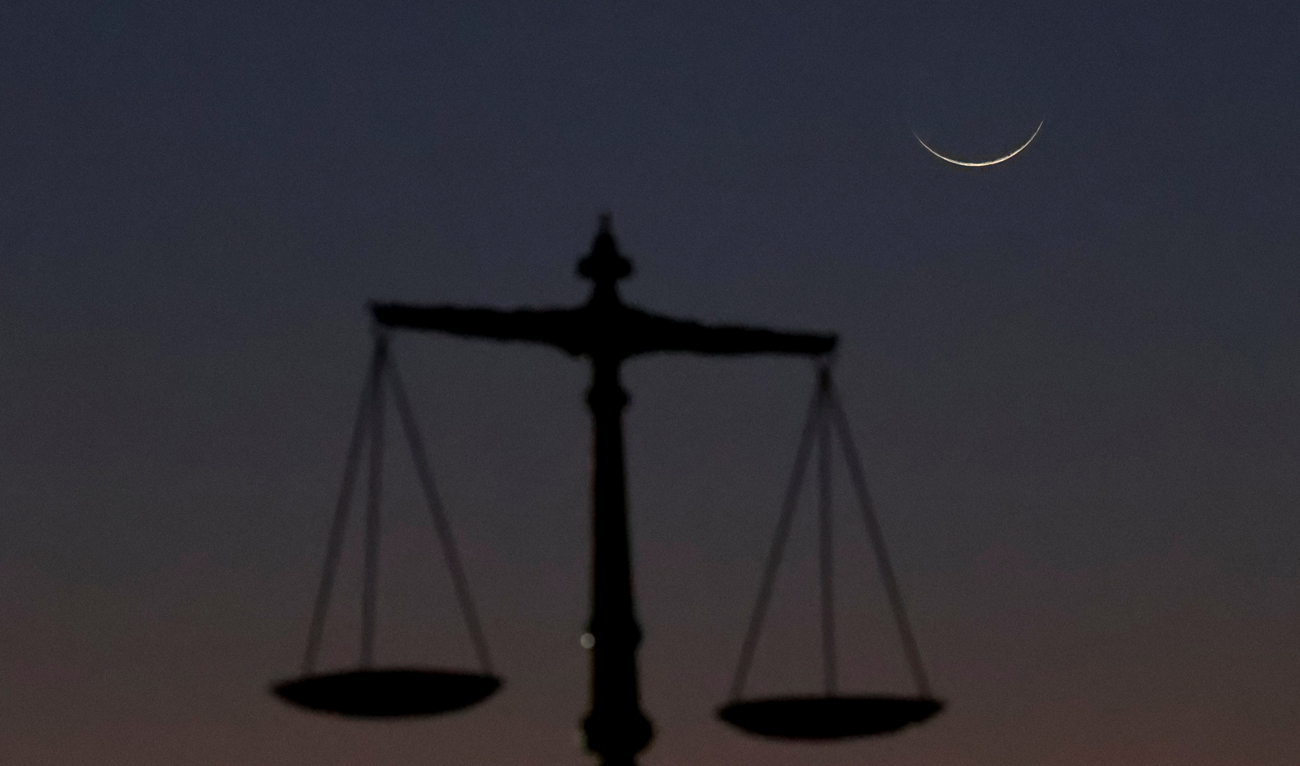 A crescent moon is seen with a monument of balance scale at the Sindh High Court premises, as Muslims attend an evening prayer session called ‘Tarawih’ to mark the holy fasting month of Ramadan in Karachi, Pakistan on March 11, 2024. (REUTERS/File)