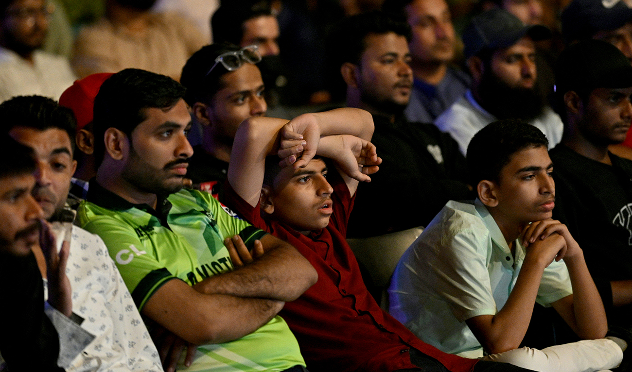 Cricket fans react as they watch a live broadcast of the ICC Champions Trophy one-day international (ODI) cricket match between India and Pakistan in Dubai, on a big in Karachi on February 23, 2025. (AFP)